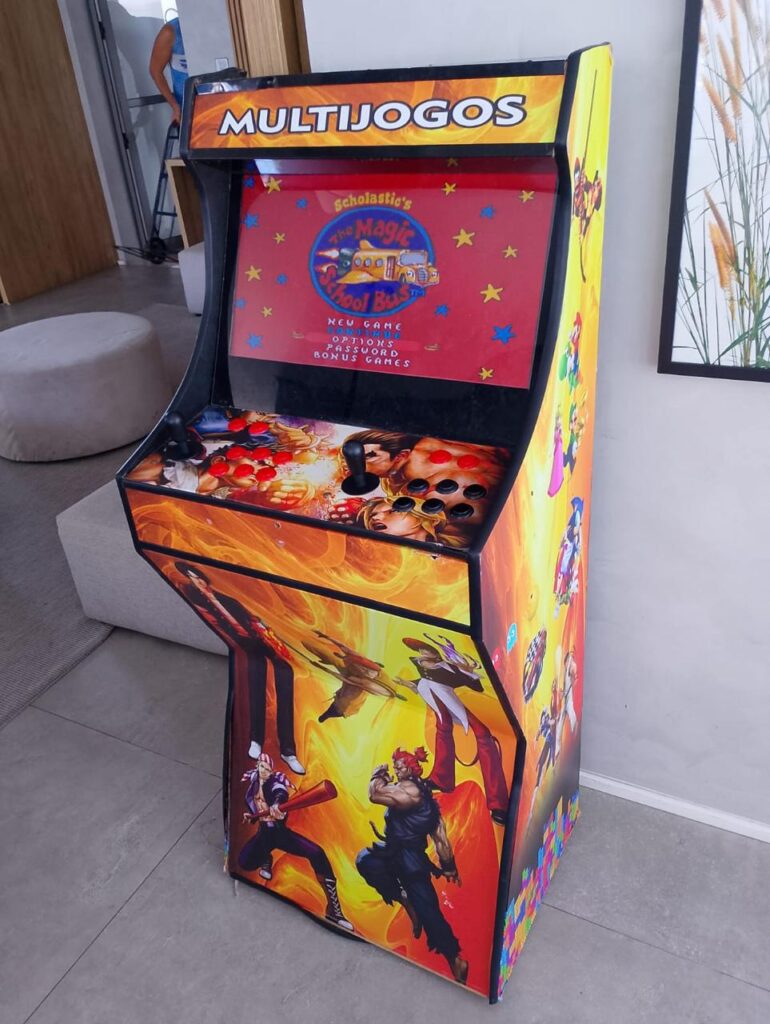 Fliperama multijogos com armário decorado, montado no canto da sala de uma casa