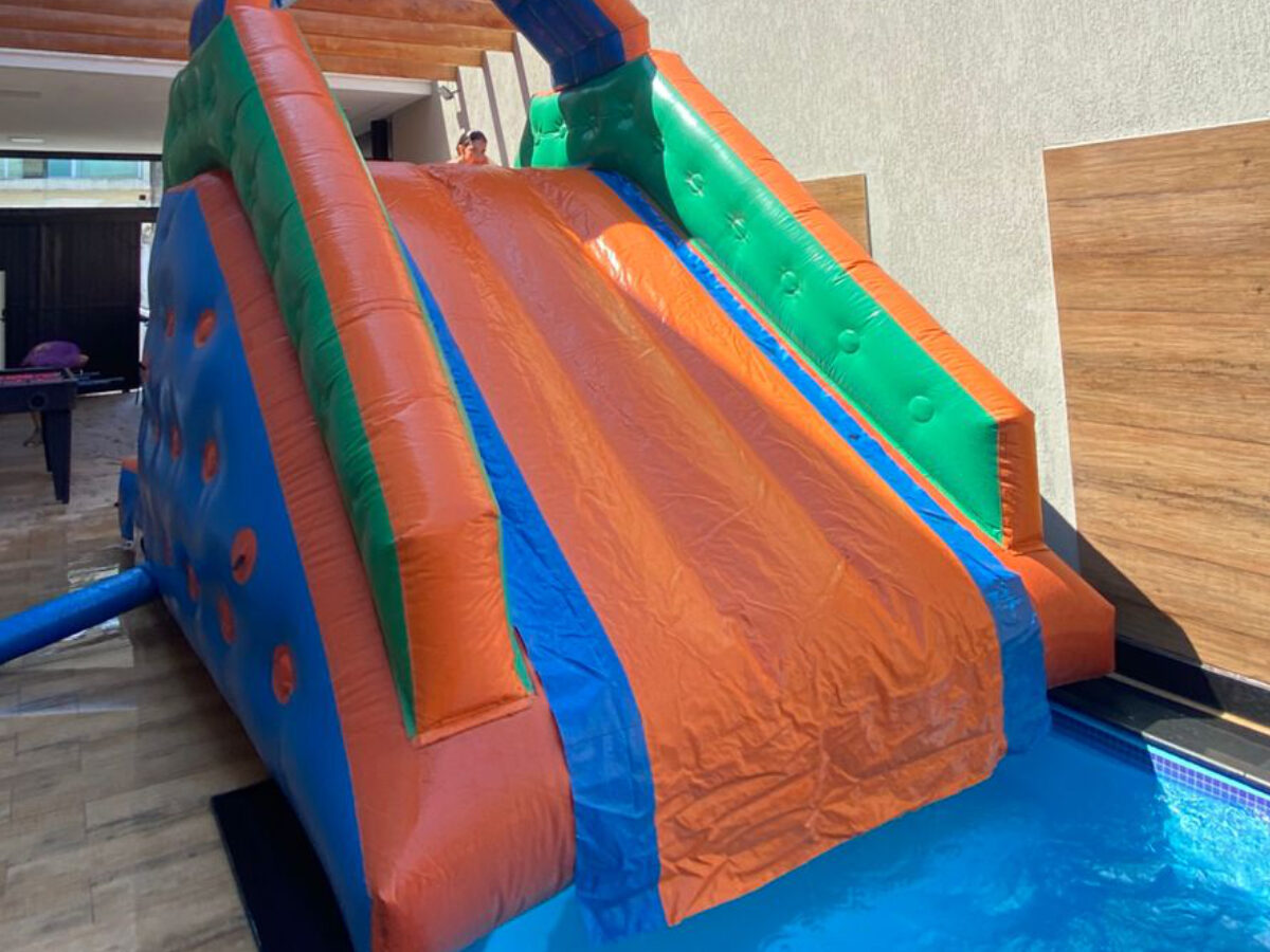 Criança descendo no escorregador aquático inflável montado na piscina, aluguel Castelinho Kids