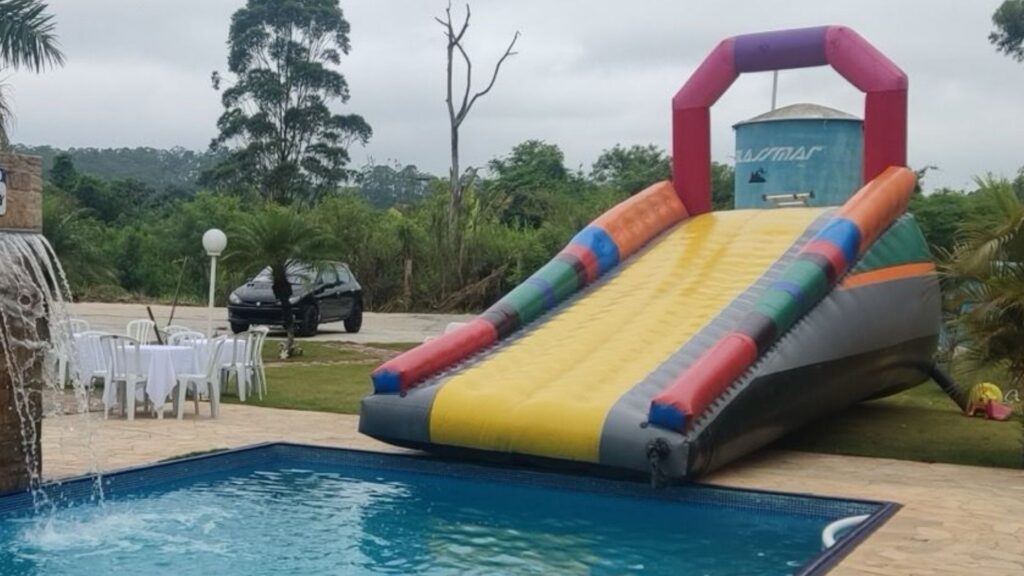 Toboágua Long montado na borda da piscina de uma chácara, com a descida terminando na água