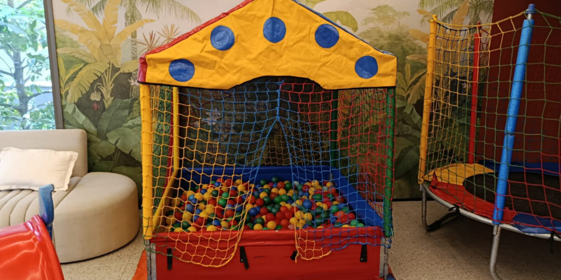 Piscina de bolinhas de armacao montada em salao de festas, com toldo colorido, rede de protecao nas laterais e colchonete na base, aluguel Castelinho Kids